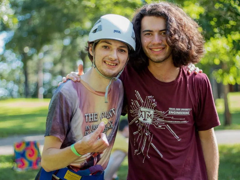 Camper wearing helmet with a long-haired camp counselor smiling for the camera